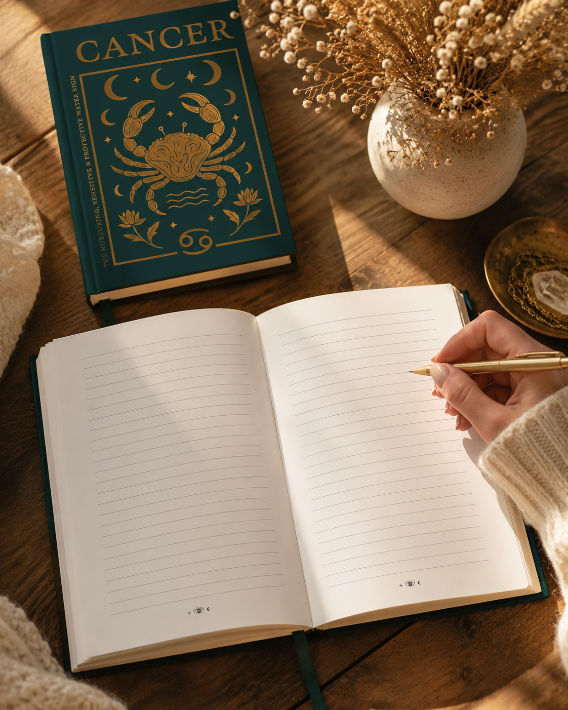 Open notebook with a hand holding a pen, next to a book titled 'Cancer' on a wooden surface.